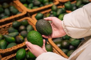 Woman choosing avocado in grocery store